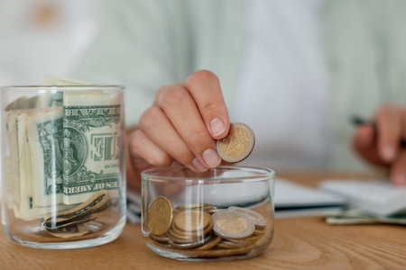 Woman putting money into jar at wooden table indoors, closeup