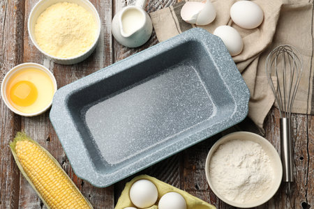 Making cornbread. Baking dish, different ingredients on wooden table, flat lay