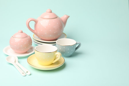 Beautiful ceramic tea set for children on turquoise background. Space for textの写真素材