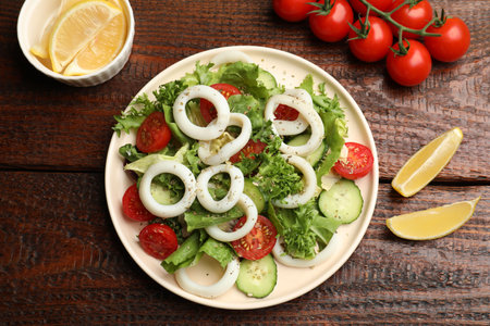 Delicious salad with squid rings, vegetables and spices served on wooden table, flat layの写真素材