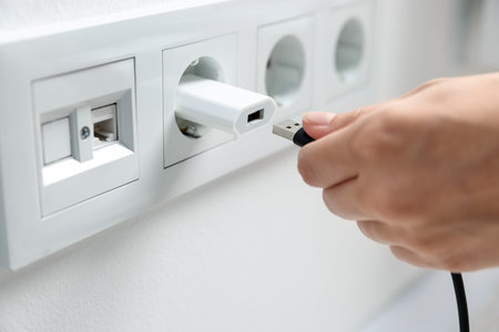 Woman inserting charge cable into USB adapter indoors, closeup