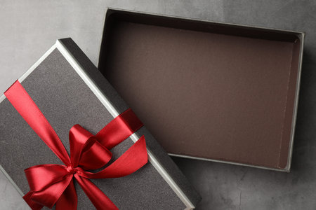 Opened gift box with beautiful lid on gray table, top view