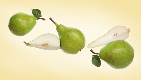 Fresh green pears flying in the air on pale orange backgroundの写真素材