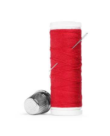 Spool of red thread with needle and thimble isolated on white
