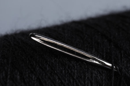 Spool of black thread with needle on gray background, closeupの写真素材