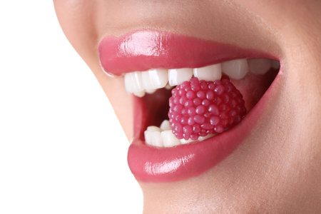 Woman with pink lipstick on her lips and raspberry candy against white background, closeup