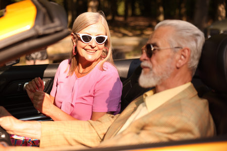 Senior couple enjoying cabriolet ride in city, selective focus