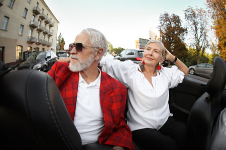 Senior couple enjoying cabriolet ride in city, wide angle lensの写真素材