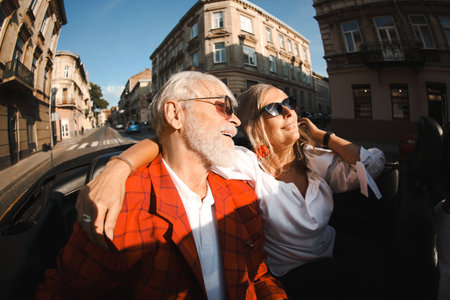 Senior couple enjoying cabriolet ride in city, wide angle lensの写真素材