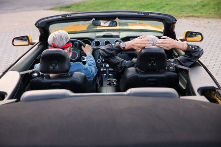 Stylish senior couple enjoying cabriolet ride outdoors, back viewの写真素材