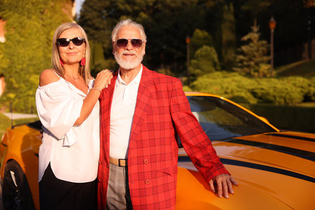 Stylish senior couple in sunglasses near modern cabriolet outdoorsの写真素材