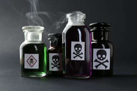 Bottles with warning signs and smoke on dark background, closeup