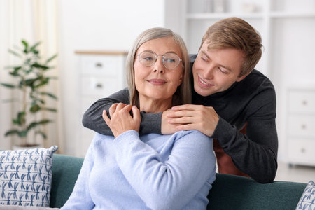 Smiling son hugging his mother at home. Family bonding