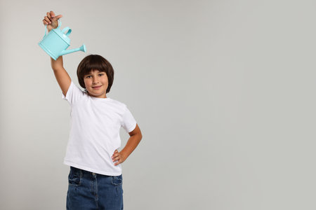 Little boy with watering can on gray background, space for text. Grow up fasterの写真素材