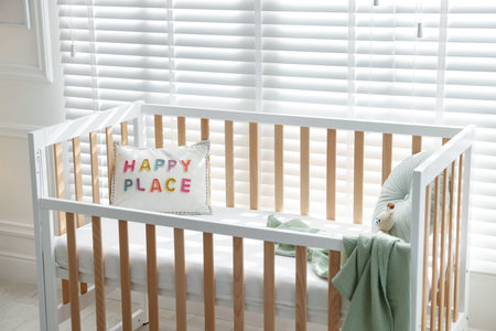 Crib with cushions, blanket and toy in baby's roomの写真素材