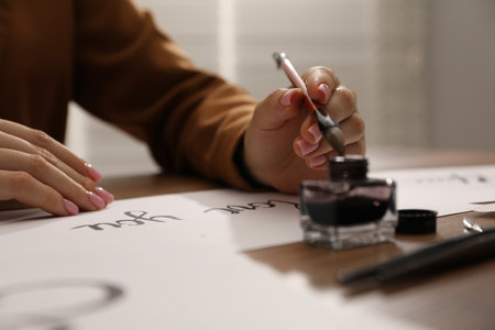 Calligraphy. Woman with brush, ink and handwritten cards at table, closeupの写真素材
