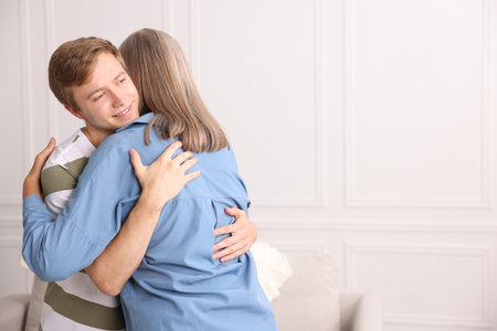 Smiling son hugging his mother at home. Space for textの写真素材