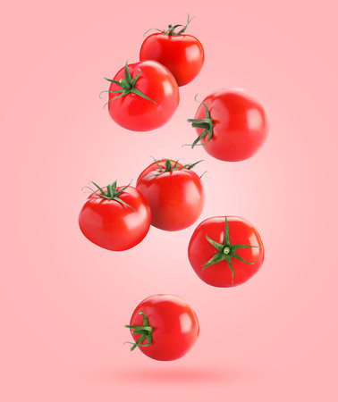 Fresh ripe tomatoes falling against pink backgroundの写真素材