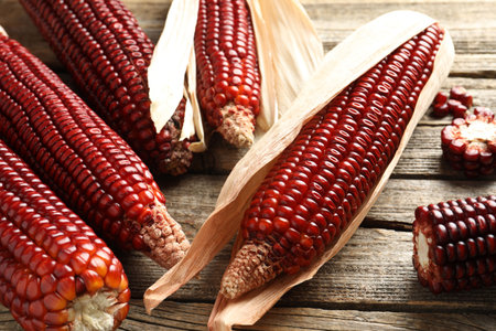 Ripe red corn cobs on wooden table, closeup