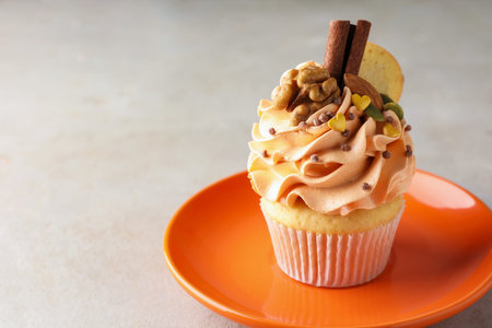 Delicious cupcake with color cream, nuts, cookies and cinnamon on gray table, closeup. Space for textの写真素材