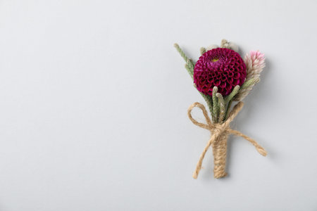 Stylish boutonniere with flowers on light gray background, top view. Space for text