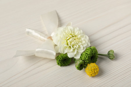 Stylish boutonniere with flowers on white wooden table, closeup