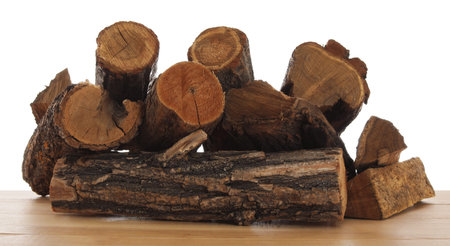 Pile of cut firewood on wooden table against white background