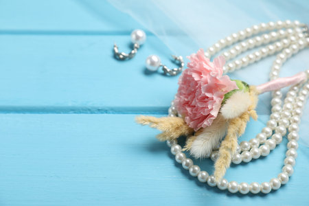 Stylish boutonniere and bride's accessories on light blue wooden table, closeup. Space for text