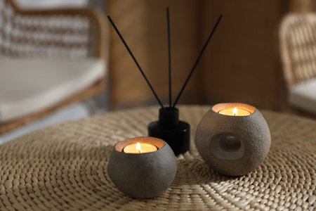 Burning candles and reed air freshener on wicker table indoors, closeupの写真素材