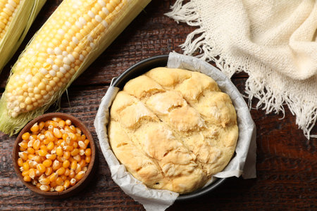 Freshly baked cornbread, seeds and cobs on wooden table, flat lay