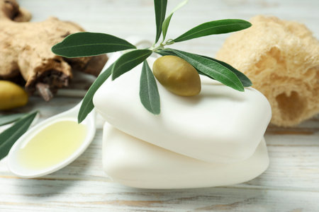 Natural soap bars with olives, oil, loofah and green leaves on white wooden table, closeupの写真素材