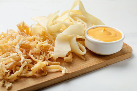 Dried shredded squid, shavings and sauce on white table, closeup