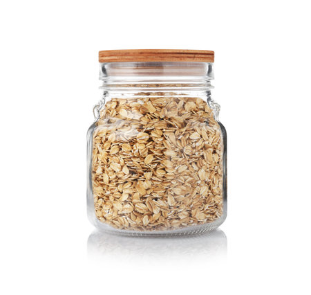 Glass jar with oat flakes isolated on white