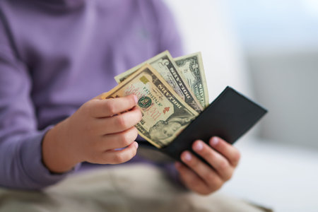 Boy putting his pocket money into wallet at home, closeup