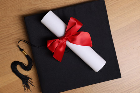 Graduation cap and diploma on wooden table, top viewの写真素材