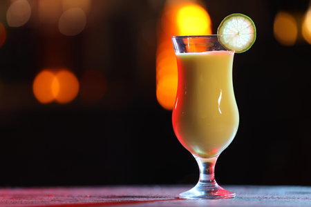 Glass of alcoholic cocktail with garnish on table against blurred background, space for text. Bokeh effectの写真素材