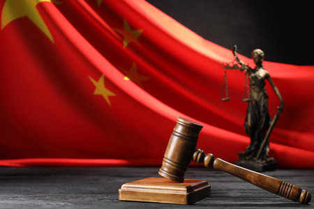 Judge's gavel and statue of Lady Justice on black wooden table against flag of China, closeupの写真素材