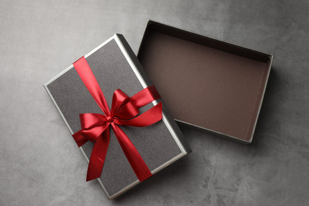 Opened gift box with beautiful lid on gray table, top view