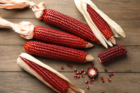 Ripe red corn cobs on wooden table, flat layの写真素材