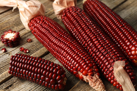 Ripe red corn cobs on wooden table, closeup
