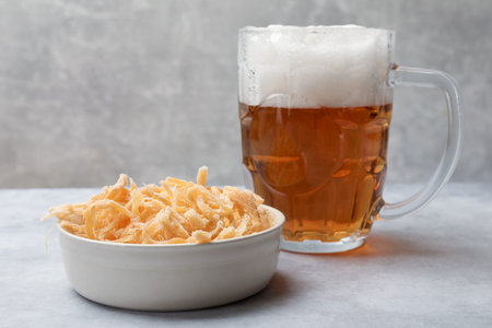 Dried squid shavings and glass mug of beer on table against gray textured background, closeupの写真素材