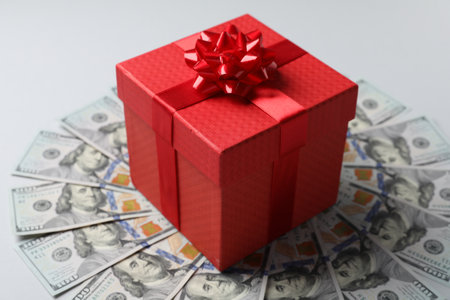 Gift box on dollar banknotes against light gray backgroundの写真素材