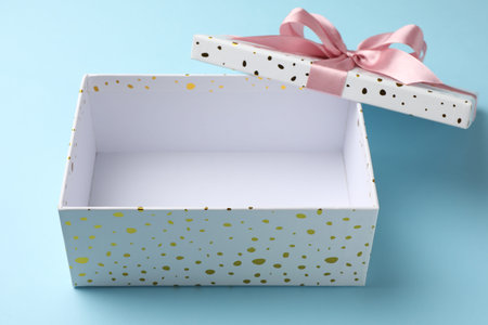 Opened gift box with beautiful lid on light blue background, closeup