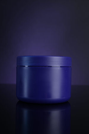 Jar of hair care cosmetic product on dark purple background