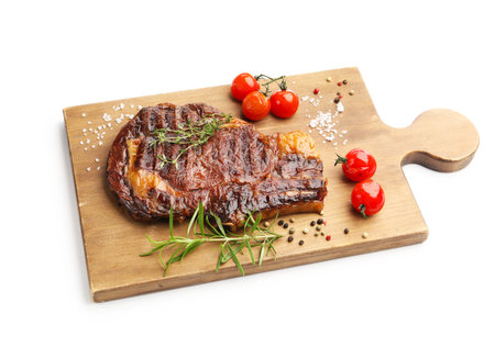 Delicious grilled beef steak with herbs, spices and tomatoes isolated on whiteの写真素材