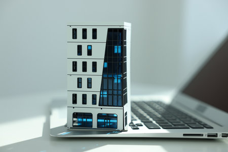 Real estate. Apartment building model and laptop on light table indoors, closeupの写真素材