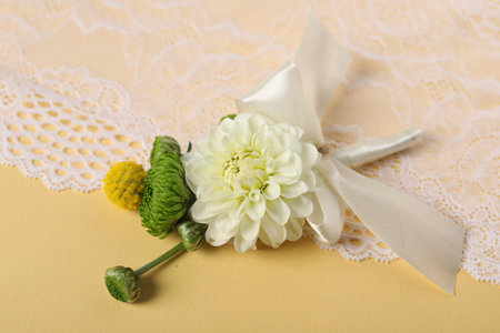 Stylish boutonniere with flowers and lace on yellow background, closeup