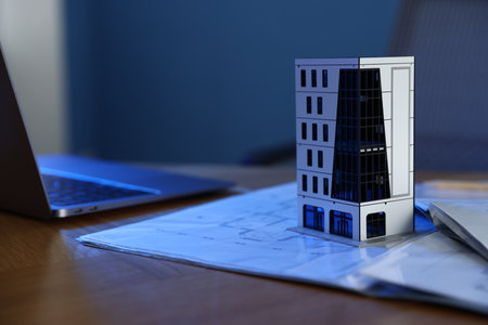 Real estate. Apartment building model, architectural drawings and laptop on table indoors, closeupの写真素材