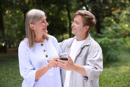 Smiling mother and her son with smartphone outdoorsの写真素材