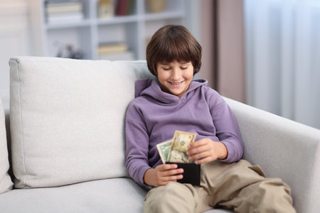 Boy with pocket money on sofa at homeの写真素材